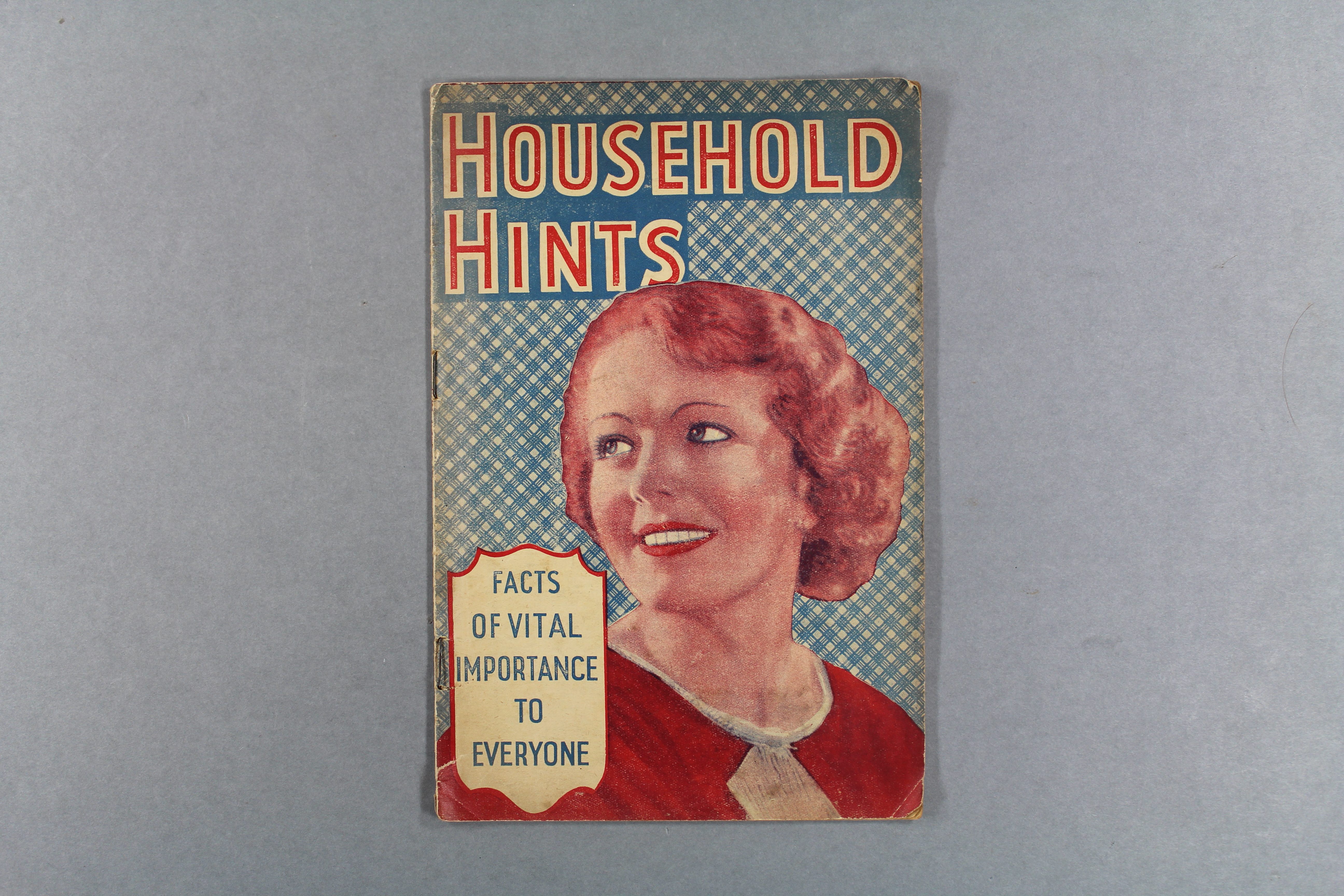 Household Hints book cover featuring a smailing woman in a 40s hairstyle. The cover is printed in shades of red and blue.